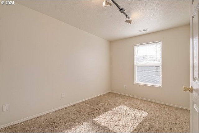 carpeted spare room featuring a textured ceiling and rail lighting