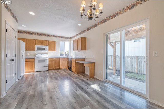 kitchen with light hardwood / wood-style floors, hanging light fixtures, a notable chandelier, a textured ceiling, and white appliances