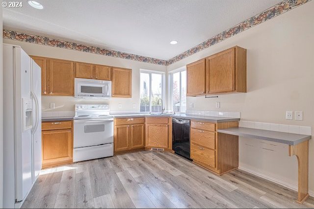 kitchen featuring white appliances, sink, and light hardwood / wood-style flooring