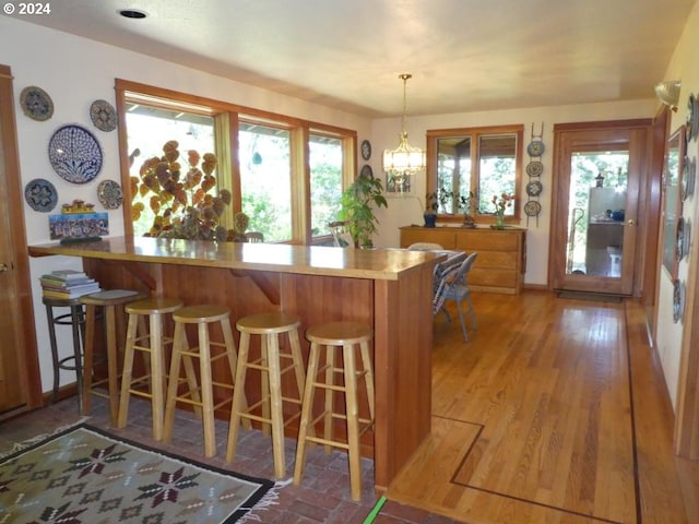 242 Rocky Point Ln, Roseburg, OR 97471 - kitchen featuring decorative light fixtures, a peninsula, a kitchen breakfast bar, wood finished floors, and brown cabinetry