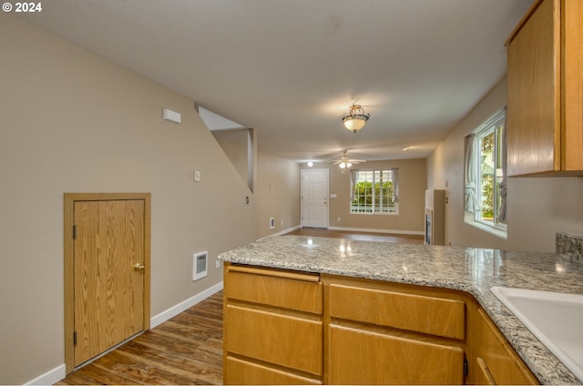 kitchen featuring sink, dark wood-type flooring, light stone counters, and ceiling fan