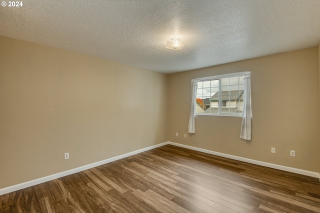 empty room with hardwood / wood-style floors and a textured ceiling