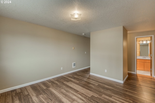 unfurnished room featuring a textured ceiling and dark hardwood / wood-style flooring