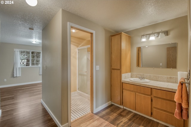 bathroom featuring vanity, hardwood / wood-style flooring, a textured ceiling, and a shower with door