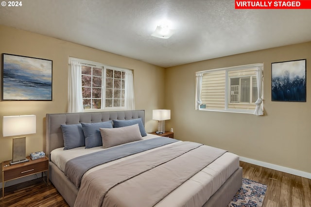 bedroom with a textured ceiling and dark hardwood / wood-style floors