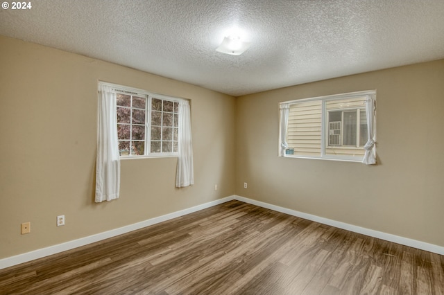 unfurnished room with a textured ceiling and wood-type flooring