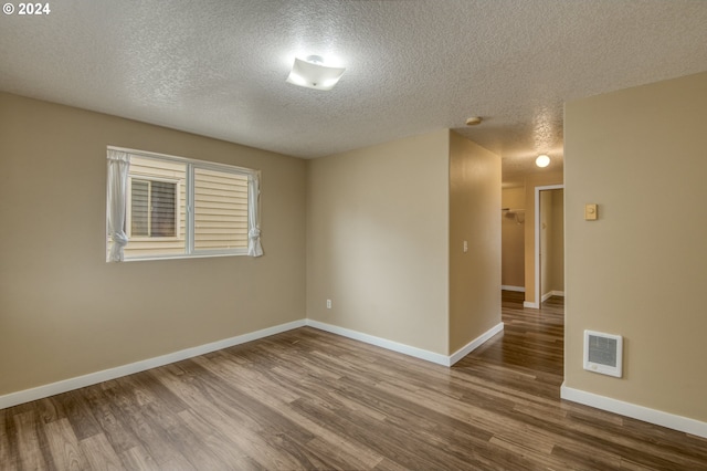 unfurnished room with a textured ceiling, hardwood / wood-style flooring, and heating unit