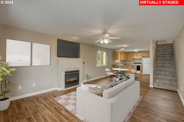 living room featuring ceiling fan, light wood-type flooring, and a high end fireplace