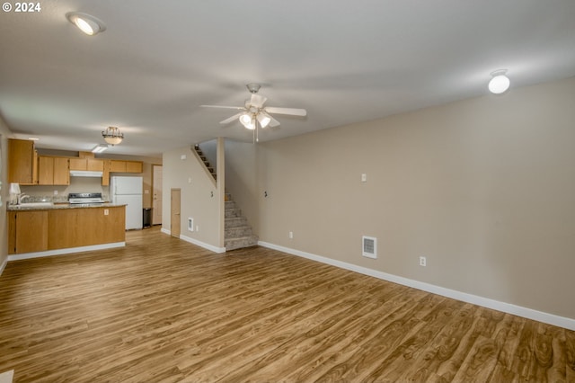 unfurnished living room with sink, light wood-type flooring, and ceiling fan