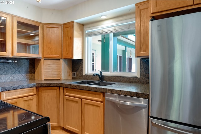 kitchen with appliances with stainless steel finishes, sink, and decorative backsplash