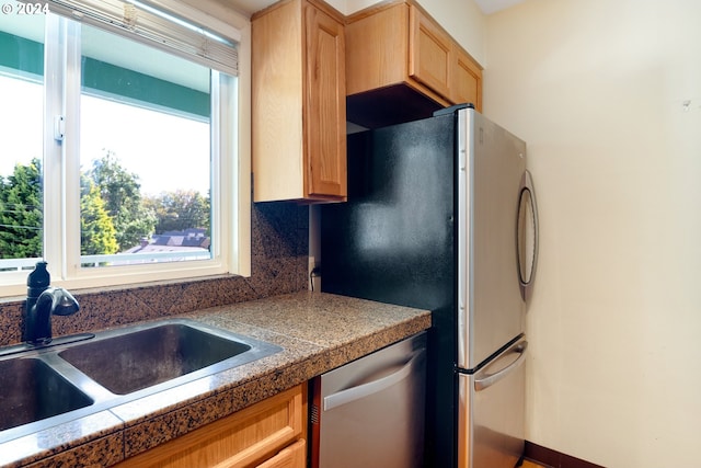 kitchen with light brown cabinetry, sink, stainless steel appliances, and tasteful backsplash