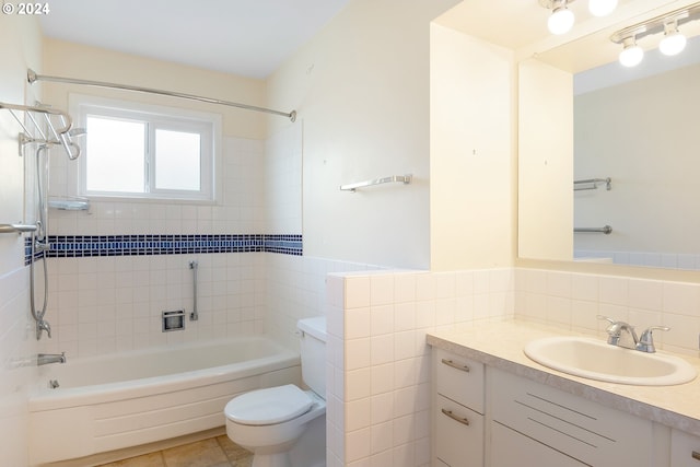 full bathroom featuring tiled shower / bath, vanity, tile patterned floors, tile walls, and toilet