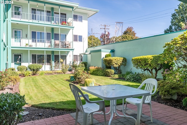 rear view of property with a balcony, a yard, and a patio