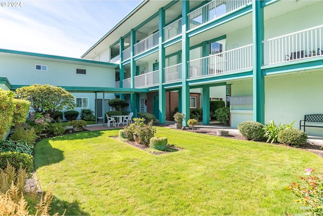 back of property with a balcony, a patio, and a yard