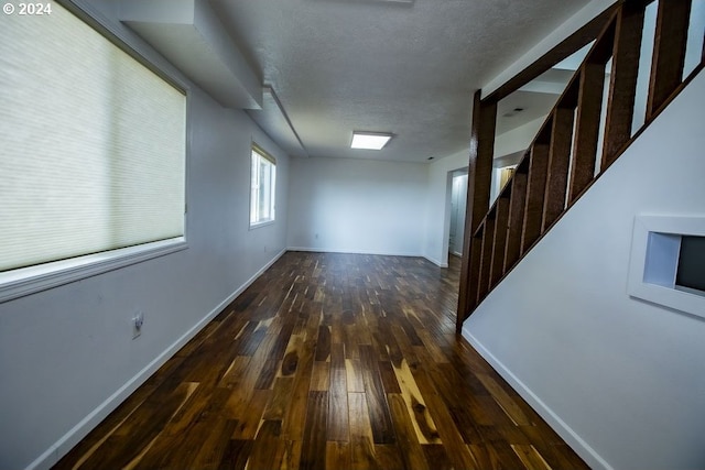 spare room with a textured ceiling and dark wood-type flooring