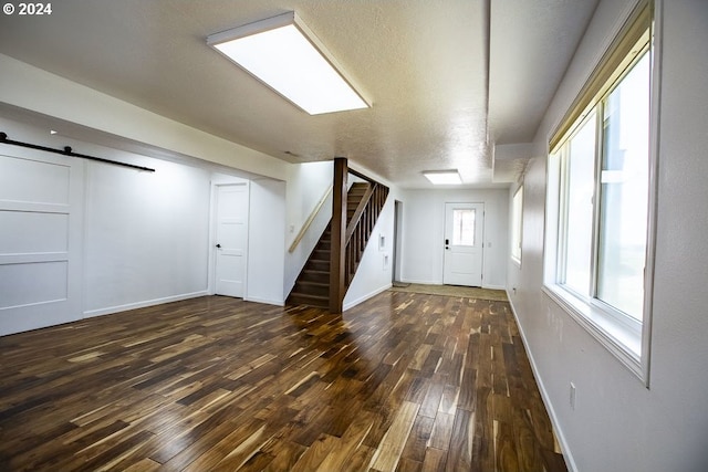 foyer featuring a textured ceiling, dark wood-type flooring, and a barn door