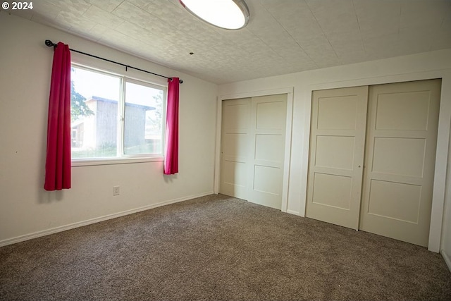 unfurnished bedroom featuring two closets and carpet flooring