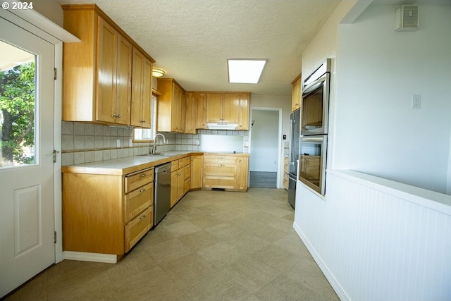 kitchen with stainless steel dishwasher, decorative backsplash, and sink