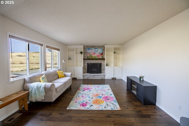 living room featuring a textured ceiling, dark hardwood / wood-style floors, built in features, and a fireplace