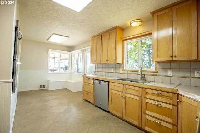 kitchen with tile countertops, dishwasher, backsplash, and sink