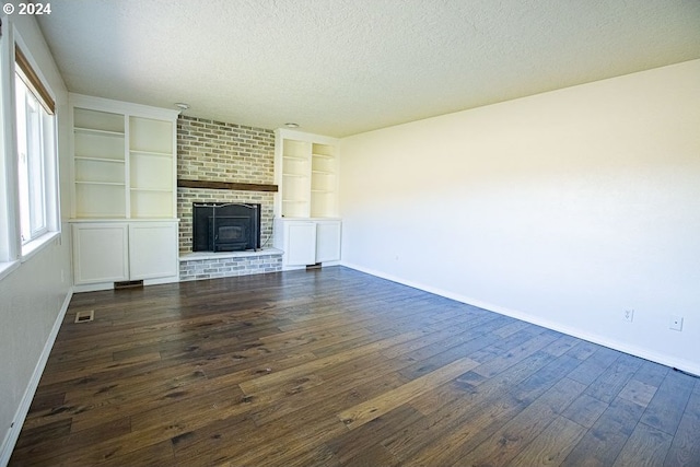 unfurnished living room with a textured ceiling, built in features, a wood stove, and dark hardwood / wood-style floors