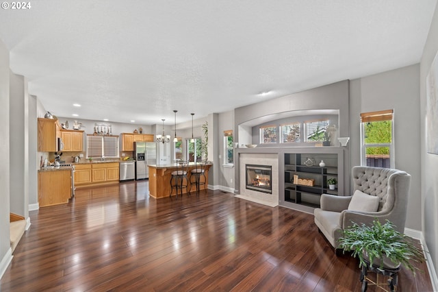 living room with dark hardwood / wood-style floors, an inviting chandelier, a textured ceiling, and a fireplace