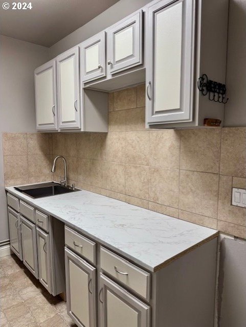 kitchen with sink, gray cabinets, and light stone countertops