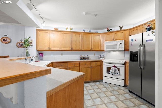 kitchen featuring white appliances, sink, kitchen peninsula, light tile patterned floors, and rail lighting