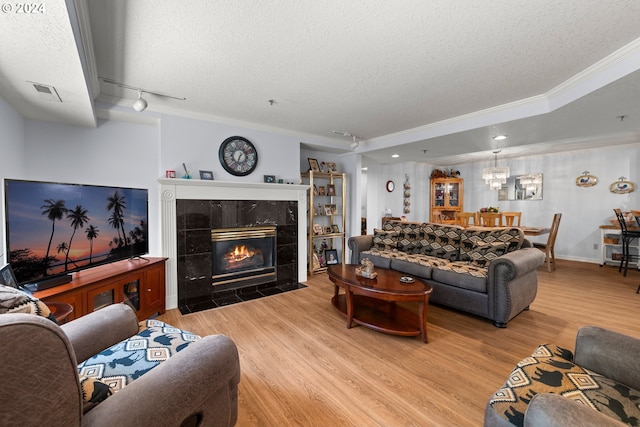 living room with crown molding, light hardwood / wood-style flooring, rail lighting, a textured ceiling, and a tile fireplace