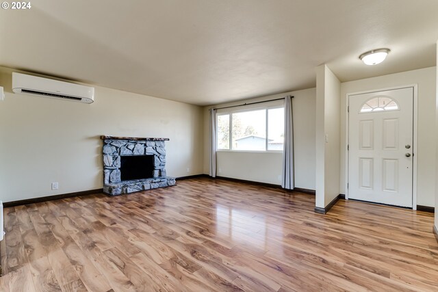 interior space with a wall unit AC, a fireplace, and light hardwood / wood-style floors