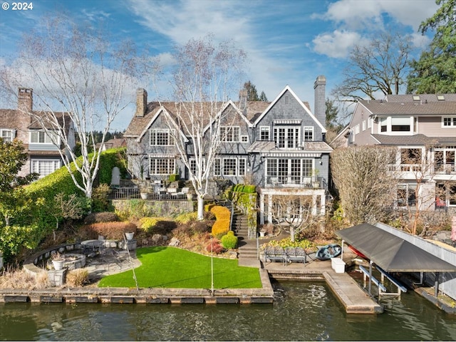 back of property featuring a lawn, a patio, and a water view