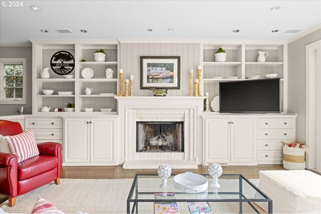 living room featuring dark hardwood / wood-style flooring, crown molding, and a brick fireplace