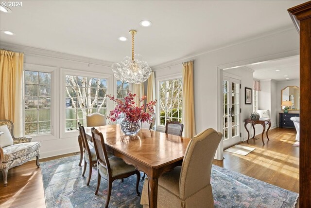 dining space with plenty of natural light, an inviting chandelier, light hardwood / wood-style floors, and crown molding