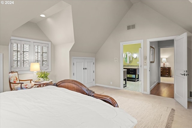 bedroom featuring a closet, connected bathroom, light carpet, and high vaulted ceiling