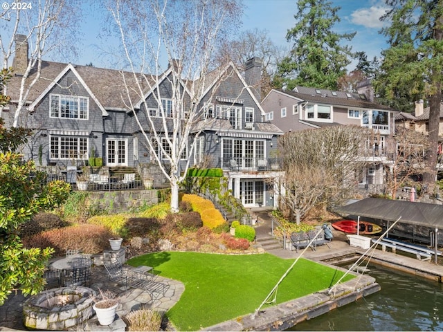 back of house with a yard, a patio, and a water view