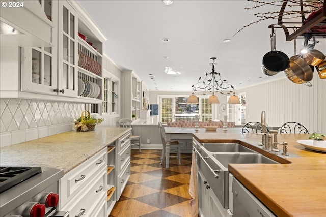 kitchen featuring pendant lighting, backsplash, sink, white cabinetry, and a chandelier