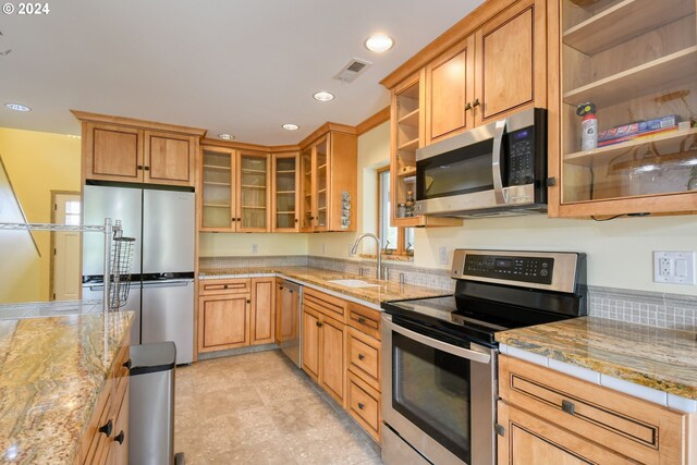 kitchen with sink, light stone countertops, light tile floors, and stainless steel appliances