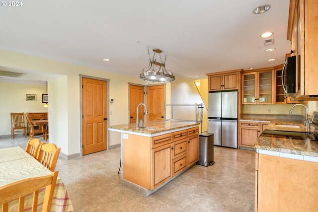 kitchen featuring appliances with stainless steel finishes, hanging light fixtures, light tile floors, and an island with sink