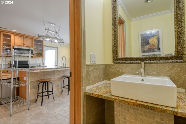 bathroom featuring tile floors, sink, ornamental molding, and tile walls