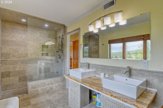 bathroom featuring dual sinks, crown molding, oversized vanity, an enclosed shower, and tile walls