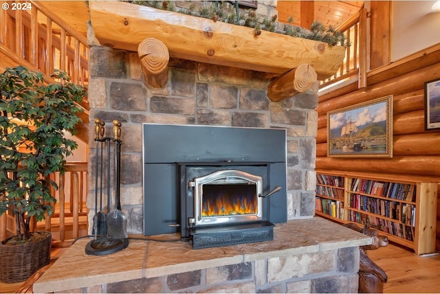 room details featuring a wood stove, log walls, hardwood / wood-style floors, and a fireplace