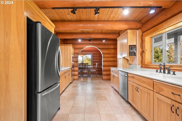 kitchen with appliances with stainless steel finishes, wood ceiling, beam ceiling, rail lighting, and rustic walls