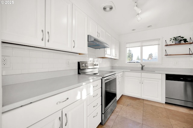 kitchen with track lighting, light tile patterned floors, white cabinets, appliances with stainless steel finishes, and sink