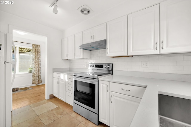 kitchen with stainless steel electric stove, white refrigerator, decorative backsplash, and white cabinets