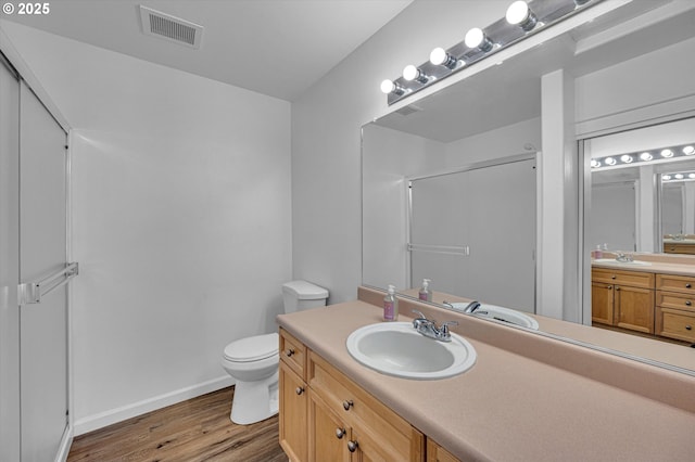 bathroom featuring vanity, toilet, a shower with shower door, and hardwood / wood-style floors