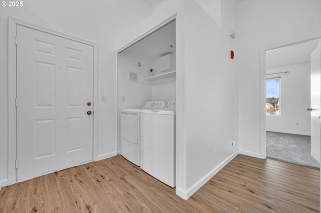 clothes washing area with washer and clothes dryer and light hardwood / wood-style flooring