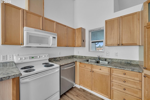 kitchen with white appliances, sink, light hardwood / wood-style flooring, and a high ceiling