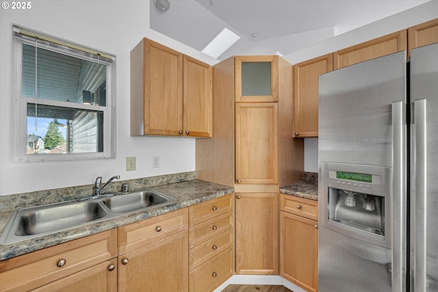 kitchen featuring stainless steel refrigerator with ice dispenser, lofted ceiling, sink, and light brown cabinets