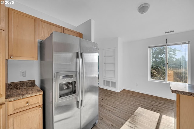 kitchen featuring light brown cabinetry, light wood-type flooring, and stainless steel refrigerator with ice dispenser