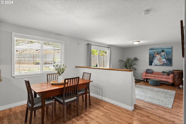 dining area with a textured ceiling and light hardwood / wood-style flooring